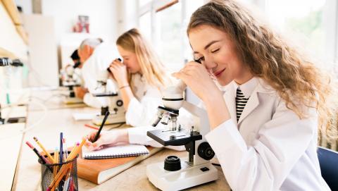 Student using microscope and science resources